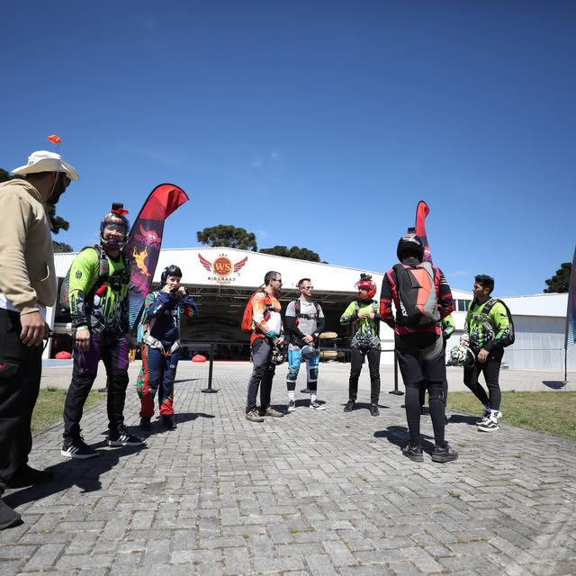 Equipe WS Skydive reunida no solo com a bandeira da escola