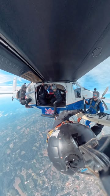 Paraquedistas deixando a aeronave pela porta em pleno voo